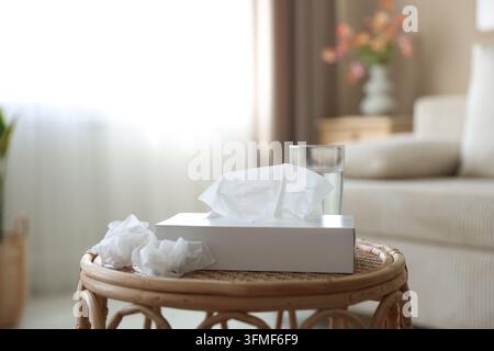 Halter mit Papiertüchern, gebrauchten Servietten und Glas Wasser auf dem Tisch im Innenraum Stockfoto