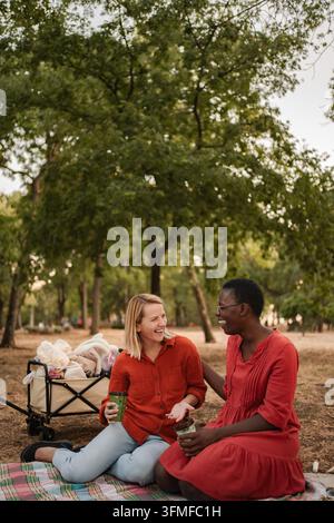 Zwei fröhliche Freunde lachen und genießen ein Picknick im Park Stockfoto