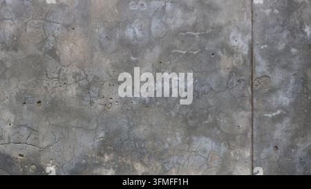 Nahaufnahme einer alten Betonwandtextur. Die unebene graue Oberfläche ist mit einem Netz feiner Risse, Streifen, Effloreszenz und dunkler Feuchtigkeit bedeckt Stockfoto