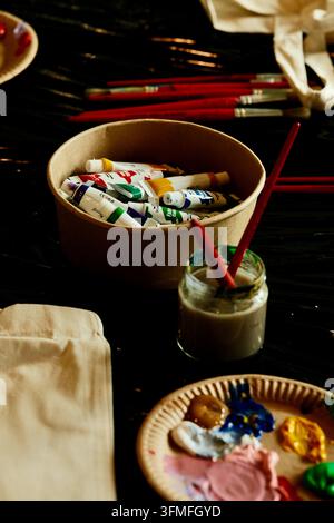 Kunstbedarf, Farbtuben, Pinsel und Palette auf einem Tisch in einem Kunststudio Stockfoto