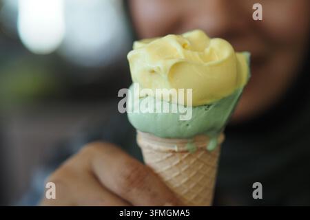 Person hält ein farbenfrohes Eis in einer lässigen Umgebung Stockfoto