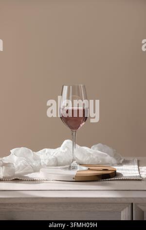 Gastgewerbe und Luxusleben, Glas Roséwein auf einem Holzbrett mit weißem Stoff in einer minimalistischen Inneneinrichtung für Marketing im Feinschmeckerbereich Stockfoto