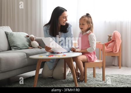 Frühkindliche Bildung und Hausunterricht, Mutter unterrichtet Tochter mit Alphabetkarten zu Hause in einem hellen Wohnzimmer für die Vorschulentwicklung Stockfoto