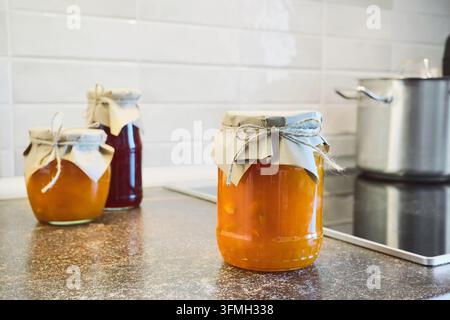 Vorbereiteter süßer hausgemachter Fruchtmarmelade und Marmelade in Gläsern auf der Küchentheke Stockfoto