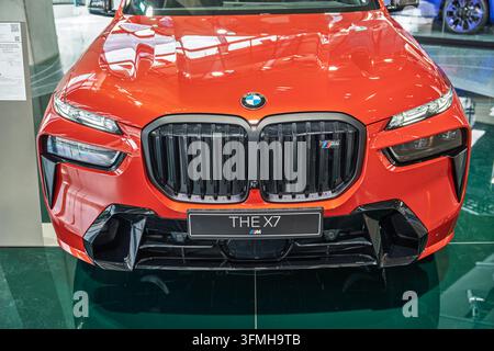 München, Deutschland, 16.07.2024 - Eine Frontansicht eines leuchtend roten BMW X7 Luxus-SUV, das sein markantes Nierengitter, scharfe Scheinwerfer und das M Sport-Abzeichen hervorhebt Stockfoto