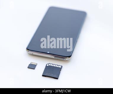 Ein modernes Smartphone ruht auf einer weißen Oberfläche mit Speicherkarten Stockfoto
