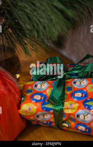 Weihnachtsgeschenke unter einem Baum mit buntem Schneemann-Einband und Schleife Stockfoto