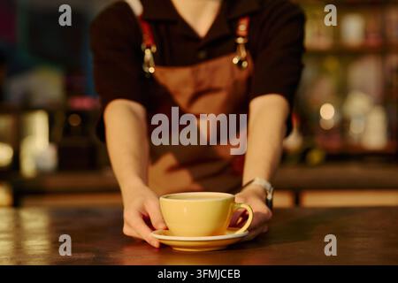 Barista serviert eine frische Tasse Kaffee an der Café-Theke Stockfoto