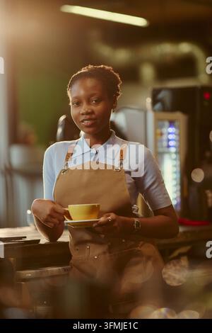 Porträt einer schwarzen Barista, die eine Kaffeetasse im Café hält Stockfoto
