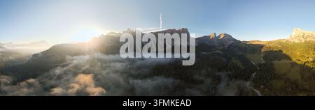 Erleben Sie einen atemberaubenden Sonnenaufgang, der goldenes Licht über die majestätischen Dolomiten in Passo Giau, Italien, wirft. Üppige Vegetation und Nebel schaffen eine ruhige Atmosphäre Stockfoto