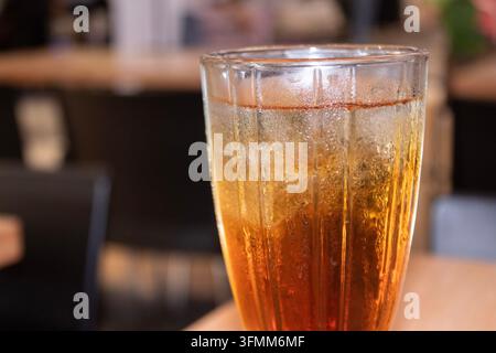 Ein Glas Eistee mit Kondenswasser, eiskalt, vor dunklem Hintergrund. Stockfoto