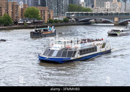 Passagiere genießen eine Stadtrundfahrt (Millenium Dawn) auf der Themse, gesehen von der Millenium Bridge in der City of London, England UK Stockfoto