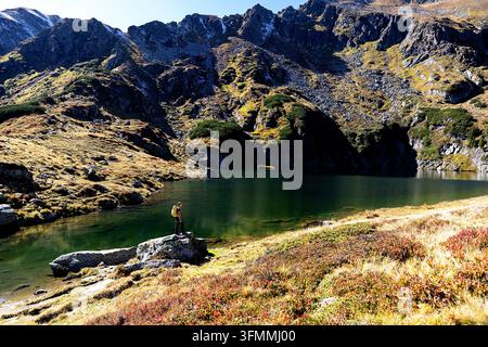 Ein Touristenwanderer mit einem Rucksack wandert einen malerischen Schotterweg durch alpine Wiesen auf der spektakulären Kaltenbachsee-Tour, Österreich. Stockfoto
