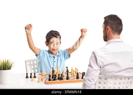 Junge, der ein Schachspiel gegen seinen Vater gewinnt, isoliert auf weißem Hintergrund Stockfoto