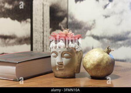 Bücher über hundert Jahre alt; die Buddha-Figur trägt eine Blume auf dem Kopf und hält eine Granatapfel, um die Bücher an Ort und Stelle zu halten. Stockfoto