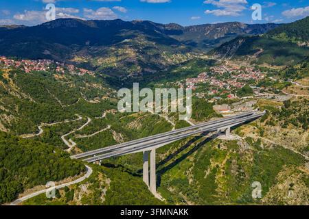 Luftaufnahme der Egnatia-Odos-Autobahnbrücke nahe Metsovo, Epirus, die ein tiefes Bergtal überspannt, umgeben von Wäldern, kurvenreichen Straßen und traditionell Stockfoto