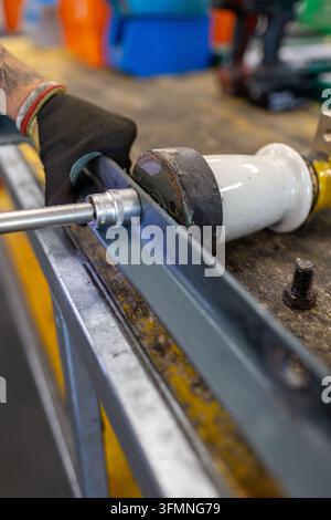 Nahaufnahme eines Industriearbeiters, der während der Wartungsarbeiten in einer Werkstatt mit einem Akku-Bohrer an einem mechanischen Bauteil arbeitet. Stockfoto
