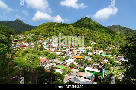 Blick auf farbenfrohe Häuser, die sich in üppigen grünen tropischen Bergen im Dorf Soufriere auf der Karibikinsel Dominica schmiegen. Stockfoto