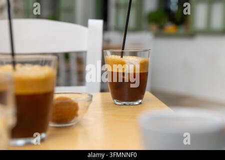 Zwei Gläser Eiskaffee mit cremiger Sahne und Eiswürfeln stehen auf einem Tisch in einer Außengastronomie auf einem Platz, eine typische Mittagspause an einem Sommertag. Stockfoto