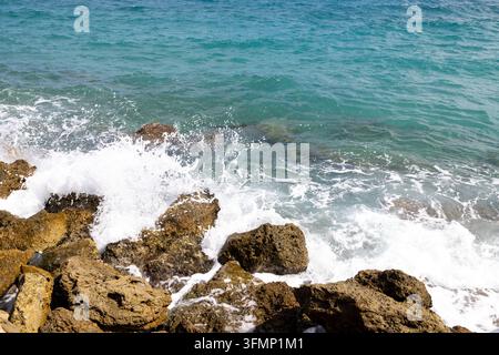 Türnisches Meerwasser bricht über schroffe Küstenfelsen mit weißem Schaum und klarem flachem Wasser und schafft eine natürliche mediterrane Küstenszene mit te Stockfoto