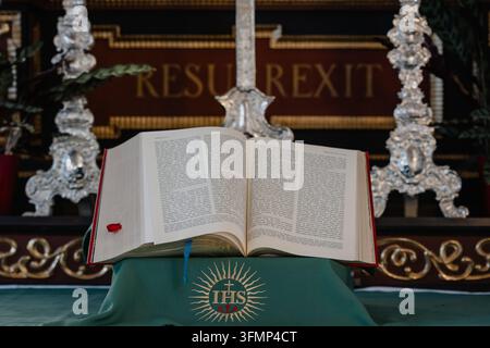 Ein offenes großes Buch auf einem Altar in einer friedlichen Kirche, das Schrift und Glauben repräsentiert Stockfoto