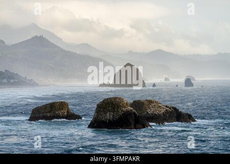 Kliffküsten und Brandung entlang von Cannon Beach und der nebligen Küste Oregons, gesehen vom Ecola State Park in Clatsop County. Stockfoto