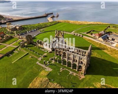 Ruinen der Whitby Abbey auf der East Cliff über dem Hafen von Whitby, North Yorkshire, Küstenlandspitze, die zu den Meeresspielfesten und der Stadt unten abfällt Stockfoto
