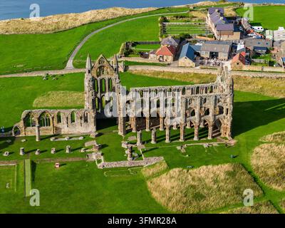 Ruinen von Whitby Abbey stehen auf einer grasbewachsenen Klippe über der Nordseeküste in North Yorkshire, gotische Bögen und Steinmauern des Schiffs von oben gesehen Stockfoto