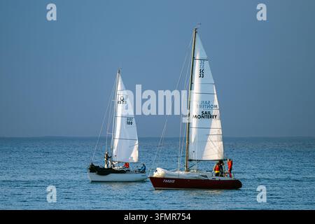 Zwei Segelboote mit weißen Segeln gleiten über blaues Wasser Stockfoto