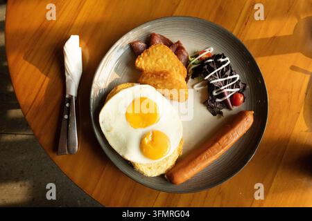 Western-Frühstücksteller mit Spiegeleiern, Hash Browns und Wurst Stockfoto