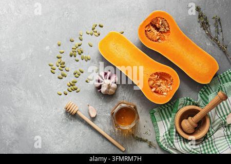 Rohe Kürbis Hälften oder butternut squash, Schneidbrett, Kräuter, Honig auf grauem Hintergrund. Ansicht von oben, flach, kopieren Raum Stockfoto