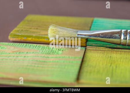 Pinsel, der auf grün und gelb lackierten Holzprobtafeln ruht Stockfoto