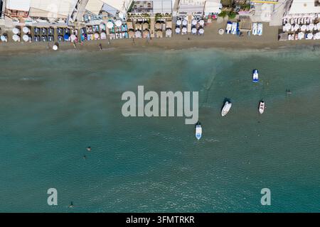 Laganas Zakynthos Griechenland Luftaufnahme von der Strandpromenade mit Sonnenliegen, Sonnenschirmen, Schwimmern, kleinen Booten und klarem Mittelmeerwasser daneben Stockfoto