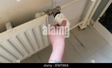 Hand, die den Heizungsregler einstellt, um die Innentemperatur zu steuern Stockfoto