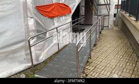 Vorübergehende Rollstuhlrampe mit Metallgeländern am Gebäudeeingang unter Renovierung Stockfoto