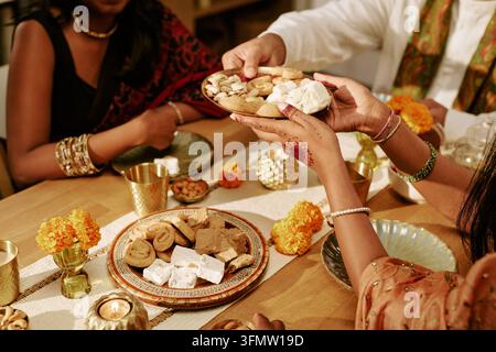 Indische Erwachsene teilen traditionelle Süßigkeiten bei einem festlichen Treffen Stockfoto