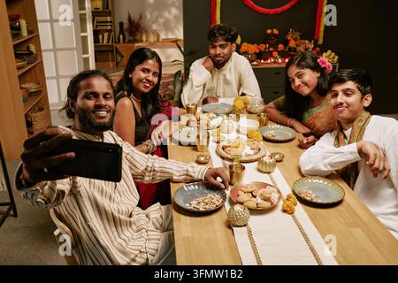 Indische Freunde, die ein Selfie mit dem Smartphone an einem festlichen Esstisch machen Stockfoto