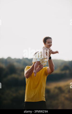Vater spielt mit glücklichem Baby im Freien bei Sonnenuntergang Familienmomente und freudige Elternschaft Stockfoto
