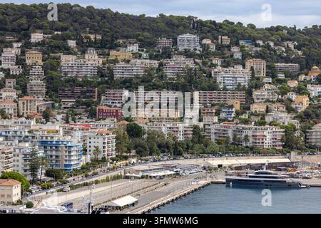 Luftbild des hügeligen Wohngebiets mit dichten Wohnhäusern, üppigen grünen Bäumen und dem Hafenbereich unten in Nizza, Provence-Alpes-Côte d’ Stockfoto