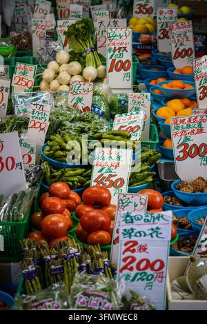 Ein Marktstand in Japan quillt über mit einer bunten Auswahl an frischem Gemüse, darunter Büschel weißer Daikon-Rüben mit grünen Köpfen, leuchtend rot Stockfoto