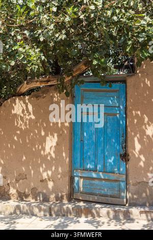 Eine rustikale blaue Tür in einer Lehmwand in der Altstadt von Khiva, Usbekistan Stockfoto