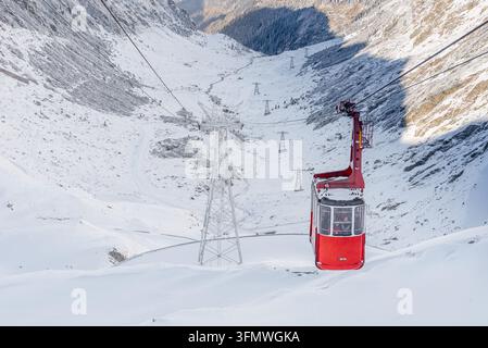 Blick auf die rote Seilbahn, die über den schneebedeckten Transfăgărăşan-Pass in den Karpaten aufsteigt, Curtea de Argeş, Kreis Argeş, Rumänien Stockfoto