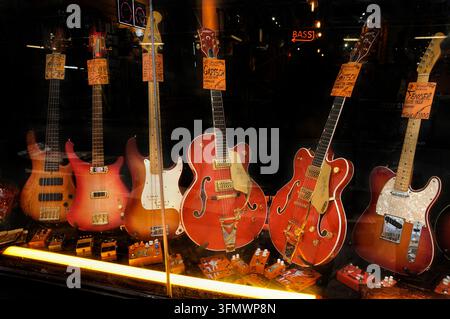 Vintage-Stil Halbakustik-/Hohlkörper-Gitarren & E-Bass in der Schaufensterauslage, Denmark Street, London UK. Orange Gretsch Nashville-Gitarre Stockfoto