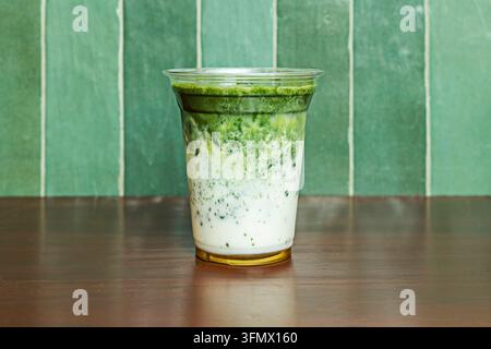 Eisgekühltes Vanille-Matcha-Getränk mit marmorierten grünen Wirbeln in einer Tasse auf einem dunklen Tisch Stockfoto