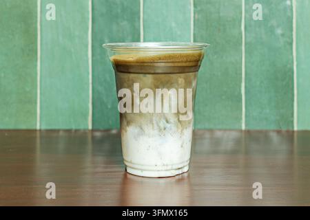 Eiskaltes Schokoladen-Matcha-Getränk mit marmorierten Schichten in einer Tasse auf einer dunklen Holzoberfläche Stockfoto