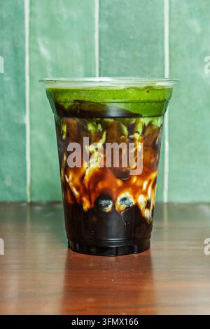 Schichtiges Eiskaltes Matcha- und Dunkler-Kaffee-Getränk mit Eiswürfeln in einem klaren Becher Stockfoto