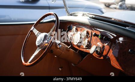 Vintage-Klassiker-Innenraum mit Holzlenkrad und Armaturenbrett Stockfoto