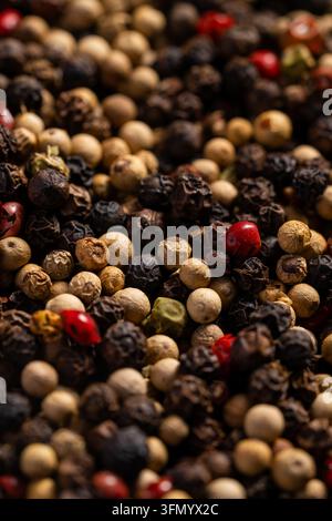Makro-Nahaufnahme einer gemischten Pfefferkornmischung mit strukturierten schwarzen, weißen, grünen und roten Pfefferkörnern. Aromatischer Gewürzhintergrund für die Küche Stockfoto