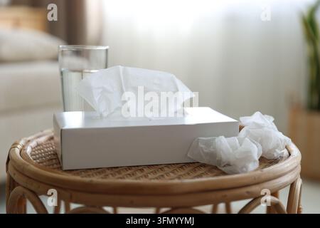 Halter mit Papiertüchern, gebrauchten Servietten und Glas Wasser auf dem Tisch im Innenraum, Nahaufnahme Stockfoto