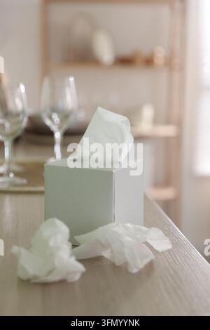 Halter mit Papiertaschentüchern und benutzten Servietten auf einem Schrank im Innenraum, Nahaufnahme Stockfoto